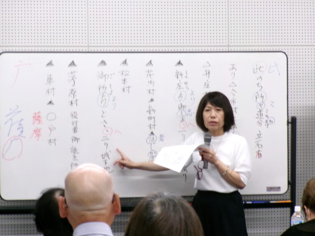 講座の画像。「御所より とさ へ」など書かれたホワイトボードを指さしながら説明する講師の先生の様子。