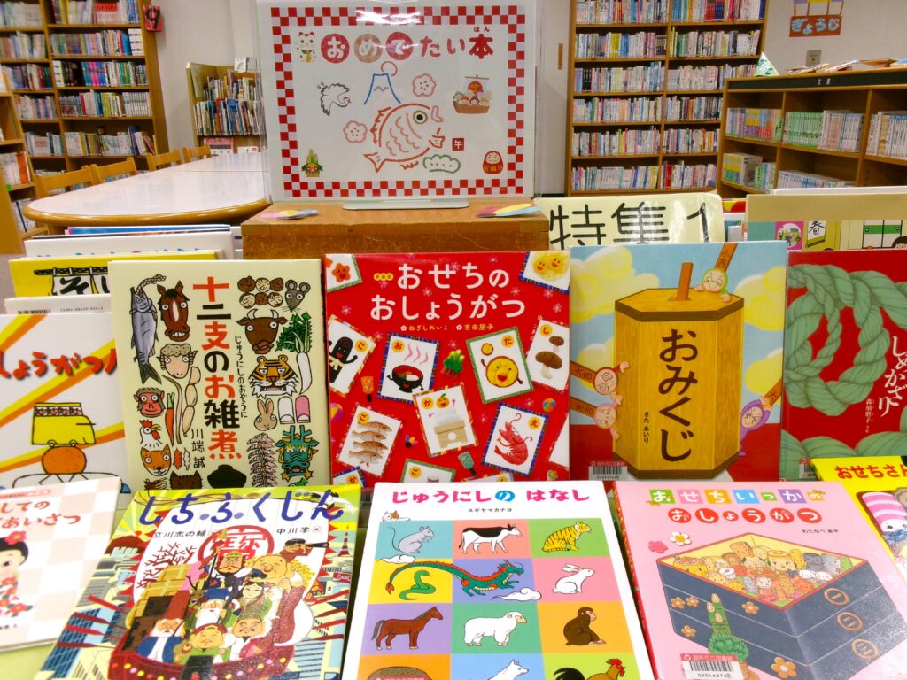 特集コーナー画像。「おめでたい本」ポスターの下に、「おせちのおしょうがつ」「十二支のお雑煮」などの本。