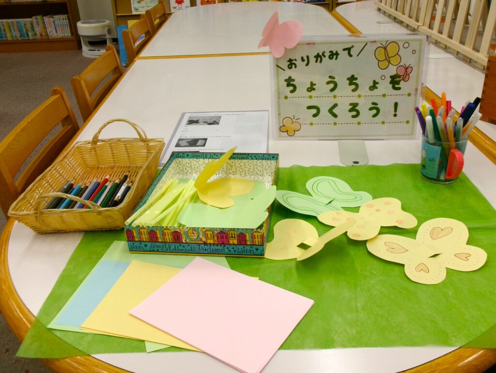 工作コーナーの画像。おりがみ、ストロー、蝶々の形に切られたおりがみ、ペン、色鉛筆。